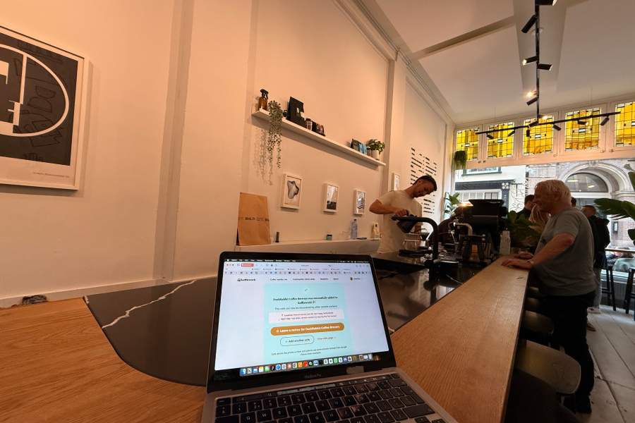 Sunlit cafe corner with built-in bench seating, bookshelves, and small tables.
